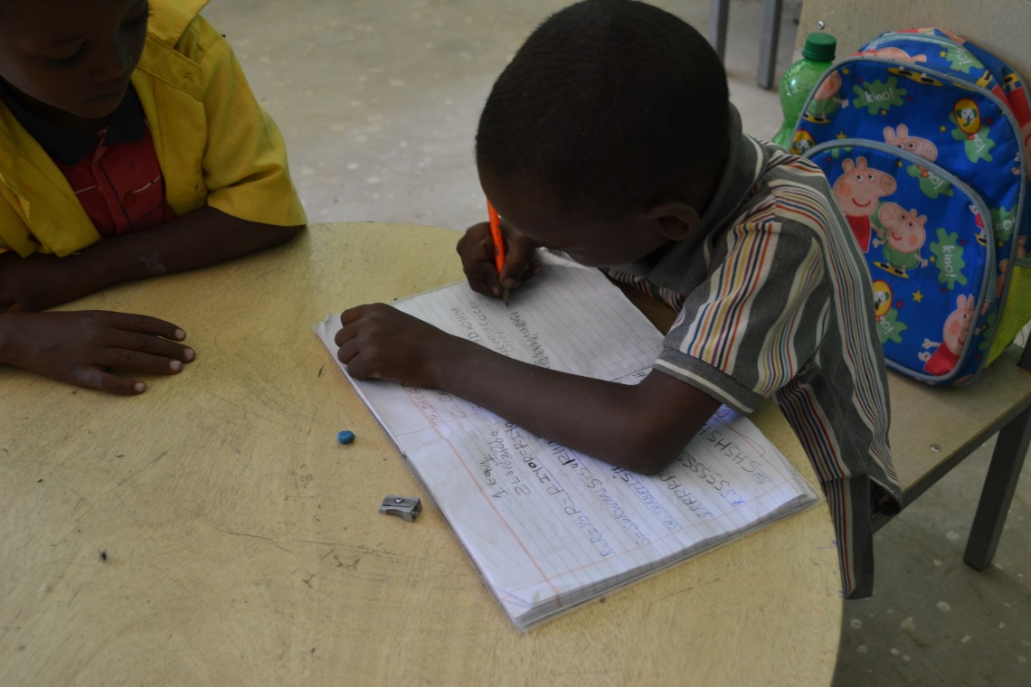 Young child in Ethiopia writing in exercise book in classroom