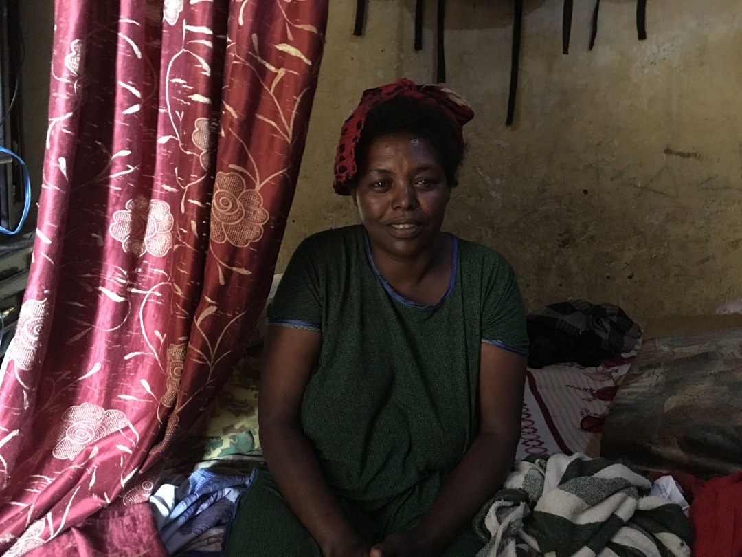 Ethiopian woman with terminal illness sitting on her bed in her home